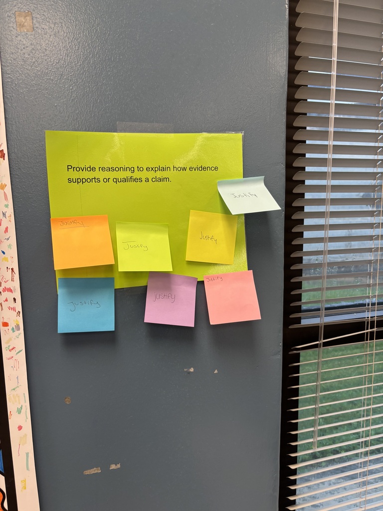 A gray door with various colored sticky notes pinned on it. Each note is a different color. The background is a window with blinds.