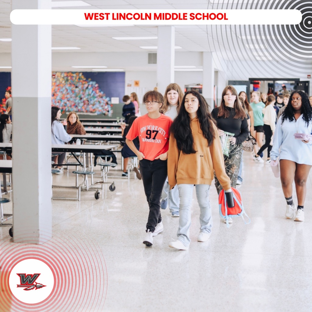 Students walk down a hallway in West Lincoln Middle School. Tables and chairs are in the background.