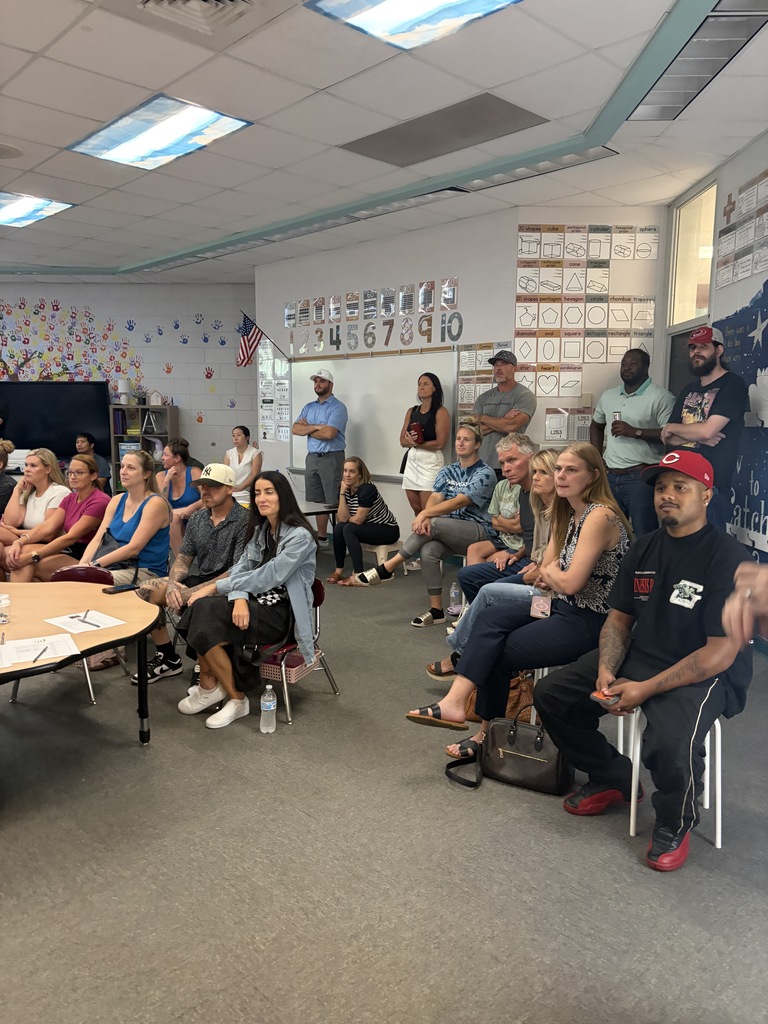 People sitting in chairs around a table in a room with a flag on the wall.