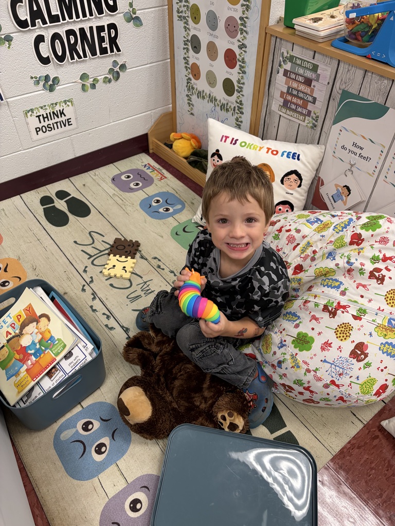 little boy in black smiling witha toy