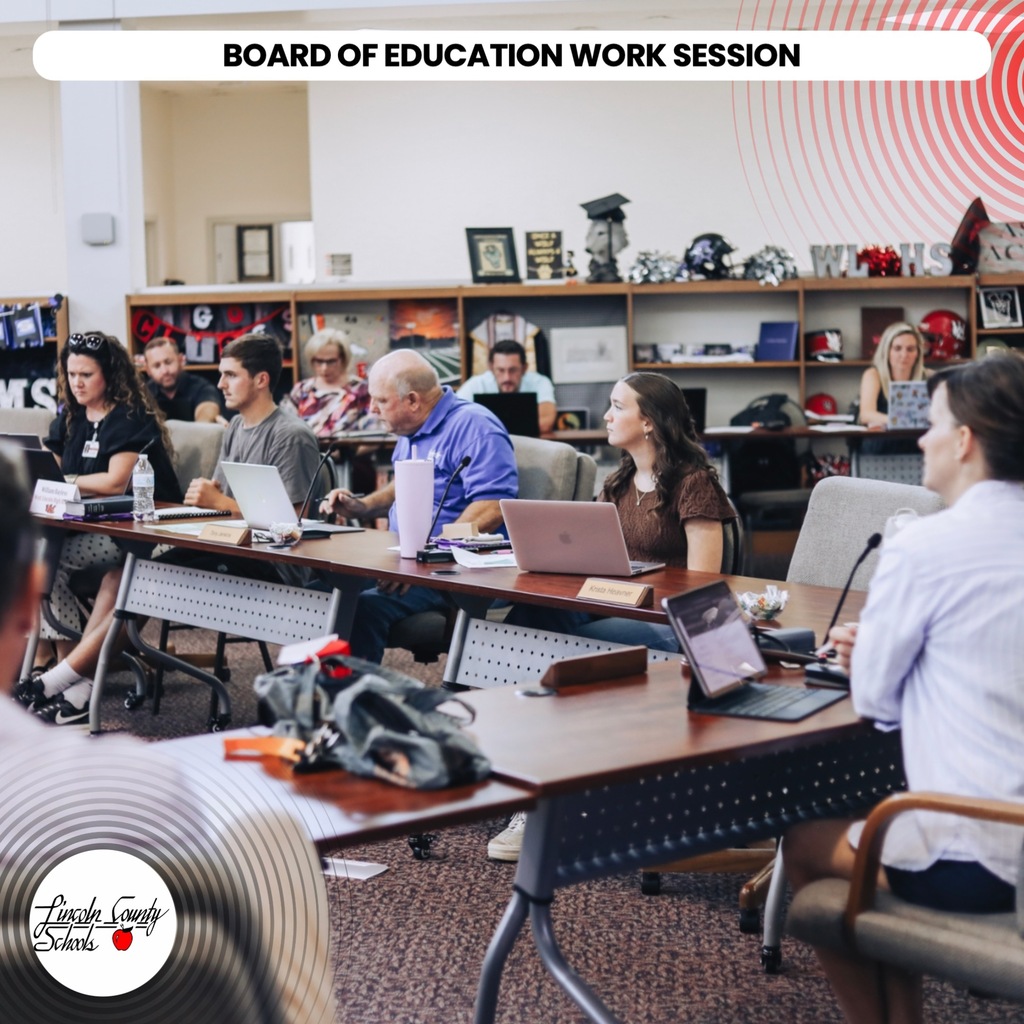 A group of people sit at tables with laptops during a Board of Education work session.