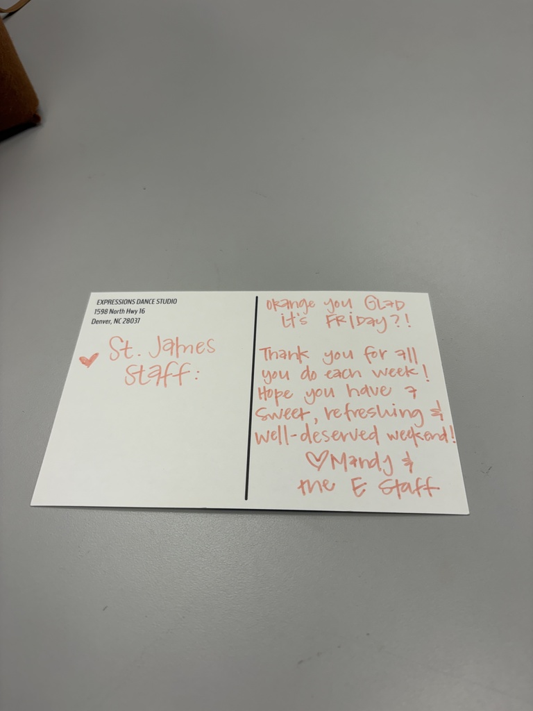 A postcard lies on a gray surface. It says "St. John's Staff" with red hearts. Handwritten text reads "Thank you! We hope you have a sweet, refreshing weekend!"