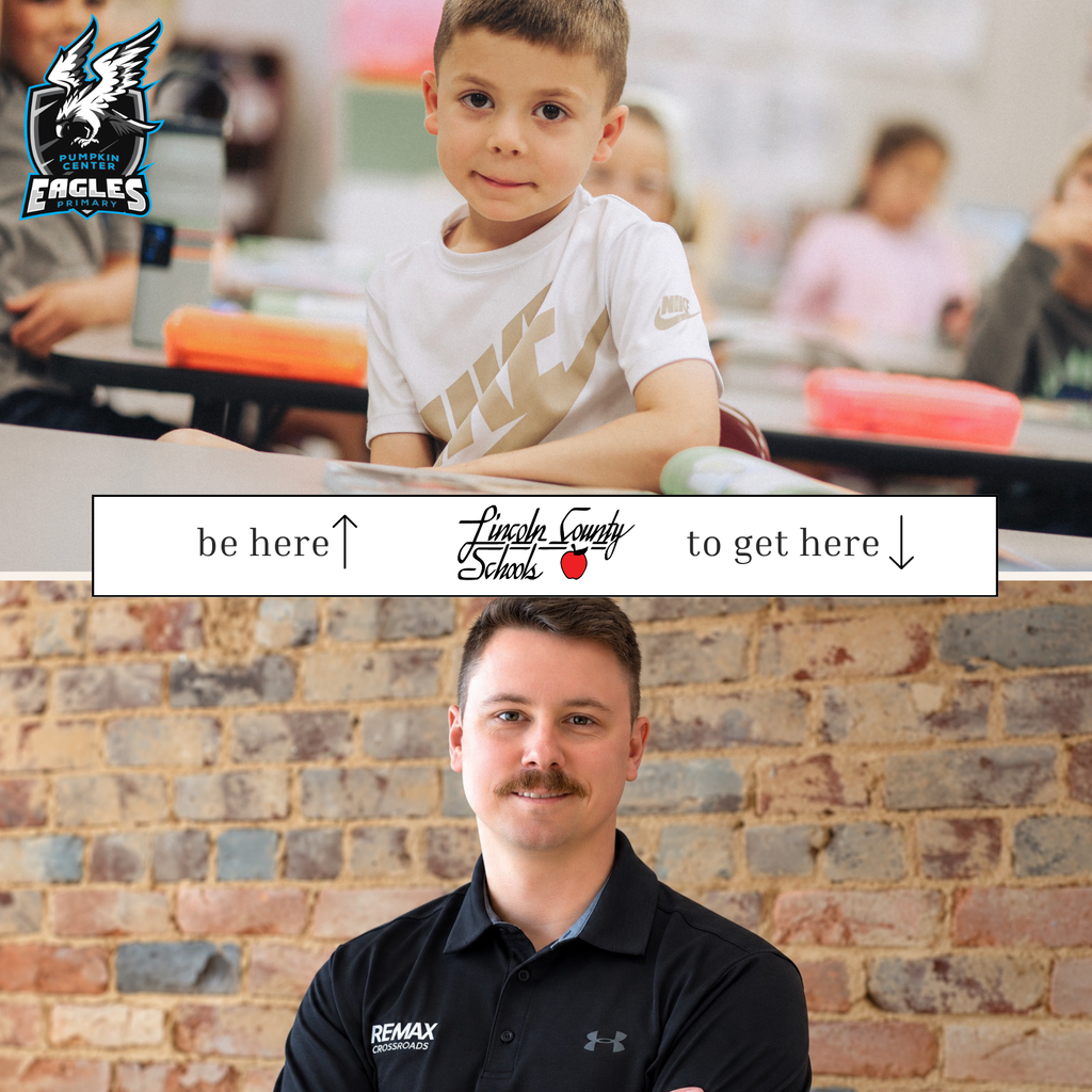 A boy sits at a desk in a classroom, and an adult stands in front of a brick wall.