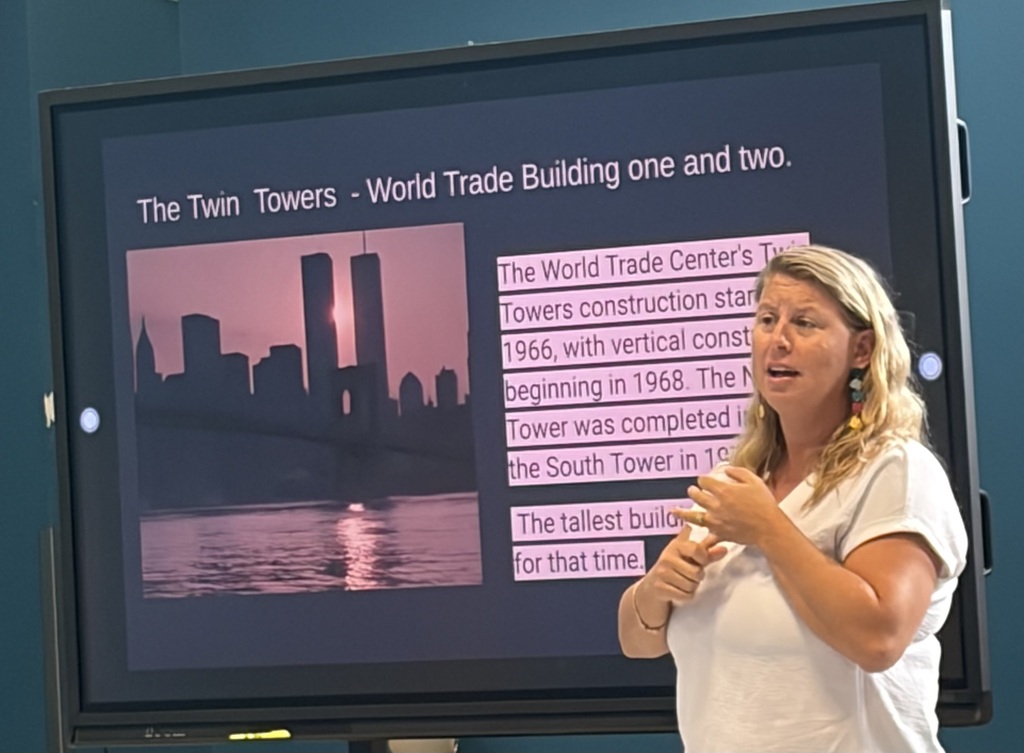 A woman stands in front of a presentation of the twin towers in New York