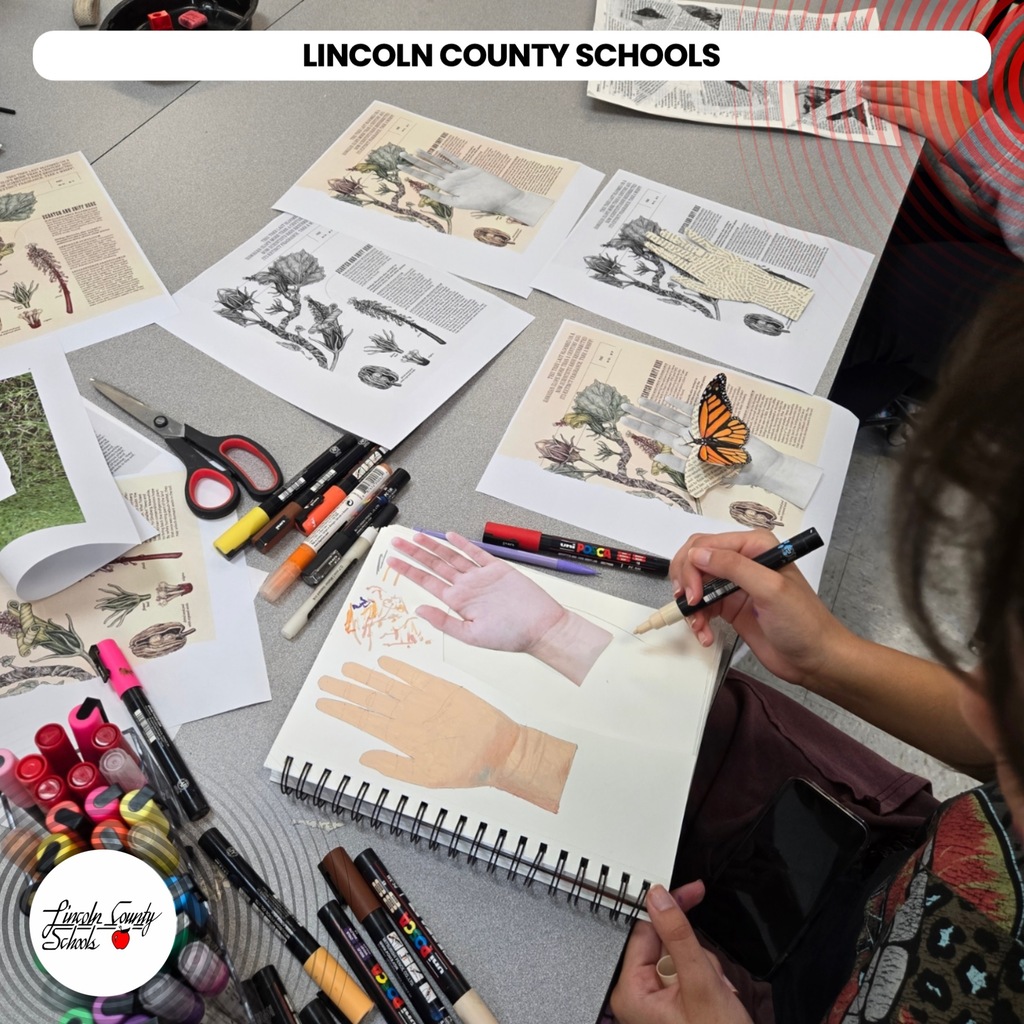 A student paints a hand on a notebook at a table filled with colored markers and scissors.
