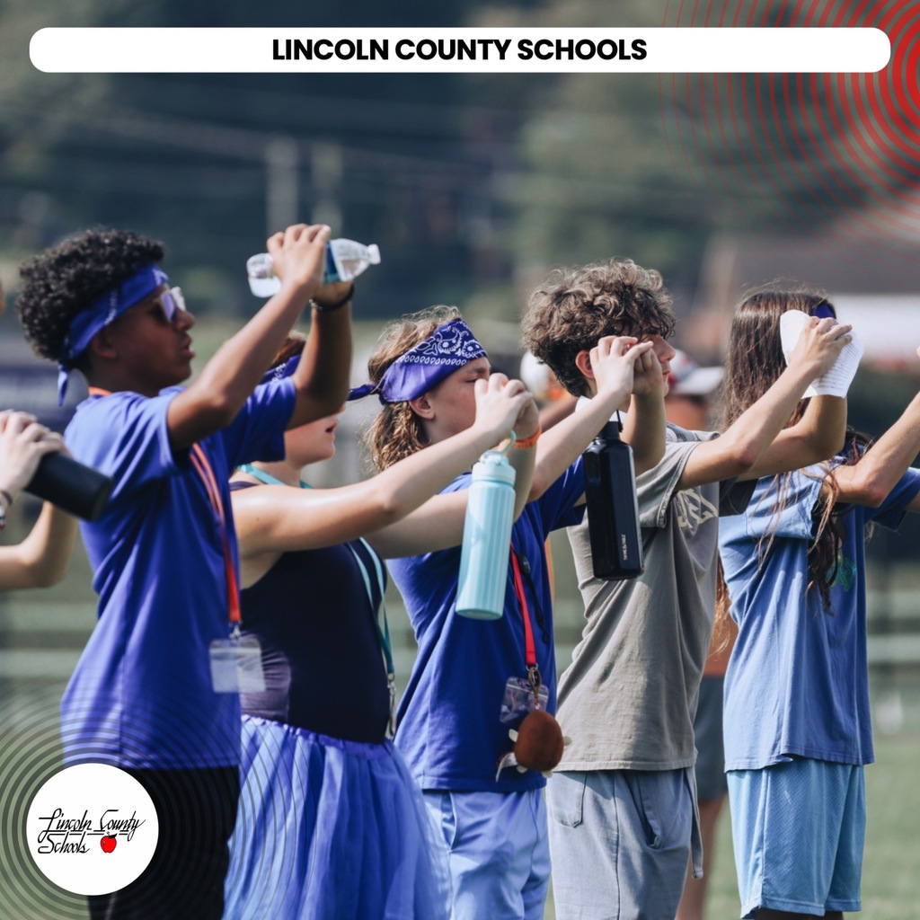 A group of students in blue uniforms holding water bottles and headbands, lined up in rows.