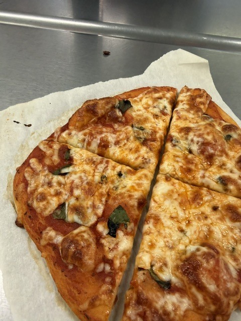 A quarter of a pizza with melted cheese and toppings rests on a paper towel.