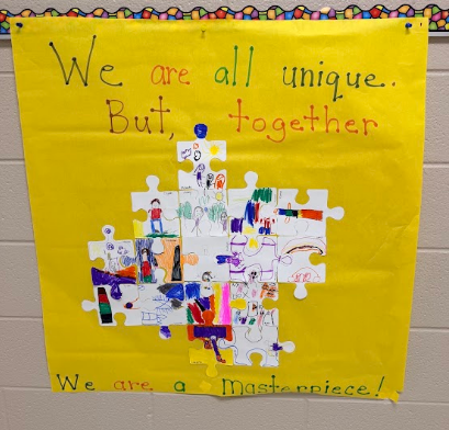 A yellow poster features a puzzle with diverse faces and figures. It reads, "We are all unique. But, together." Below, it states, "We are a Masterpiece!"