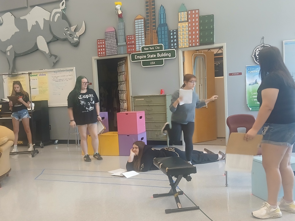 Five people in a room with a large rhino mural. One person is lying on the floor.