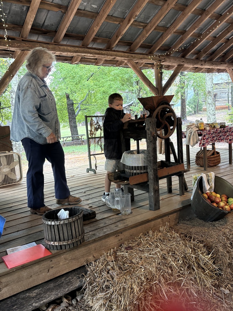 Students learning how to make apple cider on their field trip to Hart Square