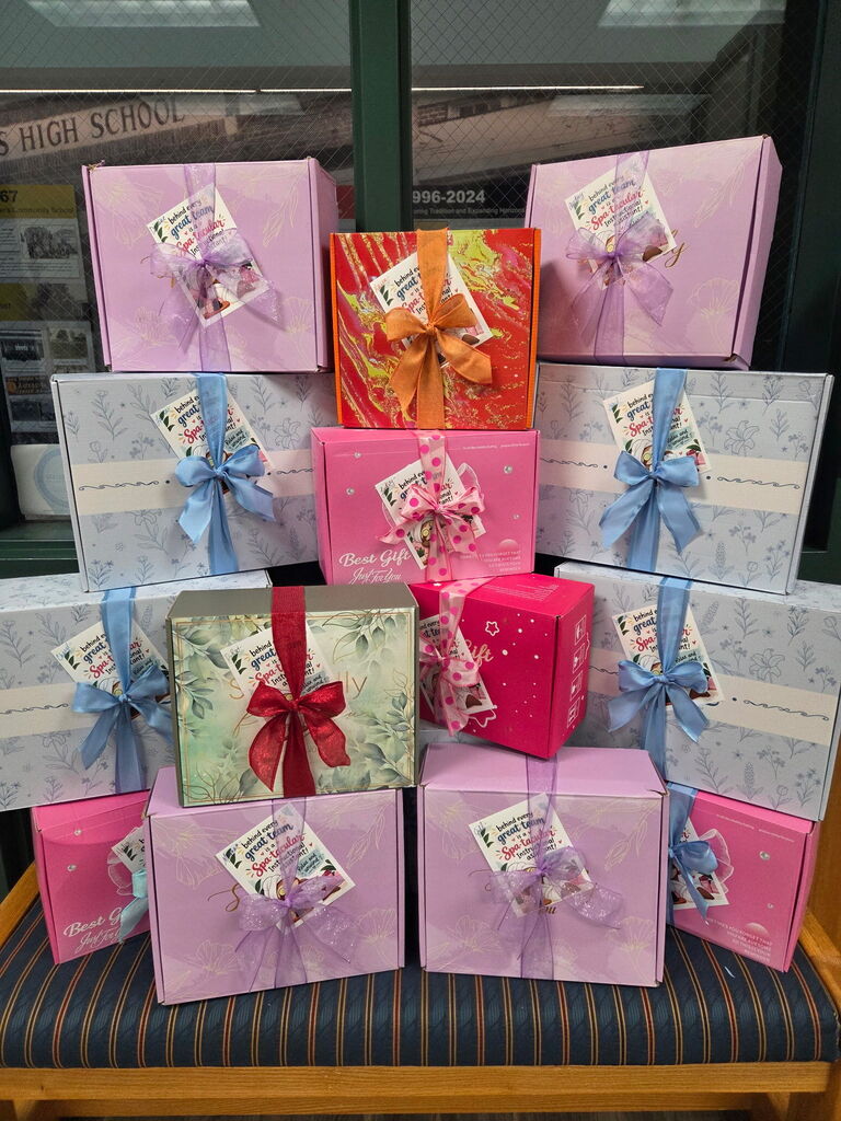 Many colorful boxes, tied with ribbons, stacked on a bench in front of a window.