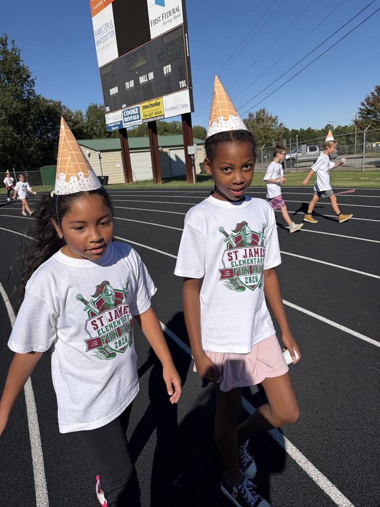 Two children in matching white T-shirts with a logo walk in a sports event. One wears a party hat.