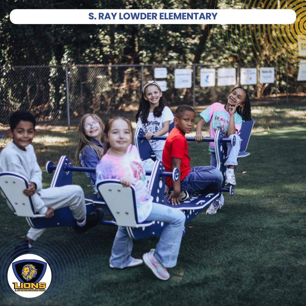 Children sitting on a seesaw in an outdoor playground. They are wearing casual clothes. A logo is at the bottom left.