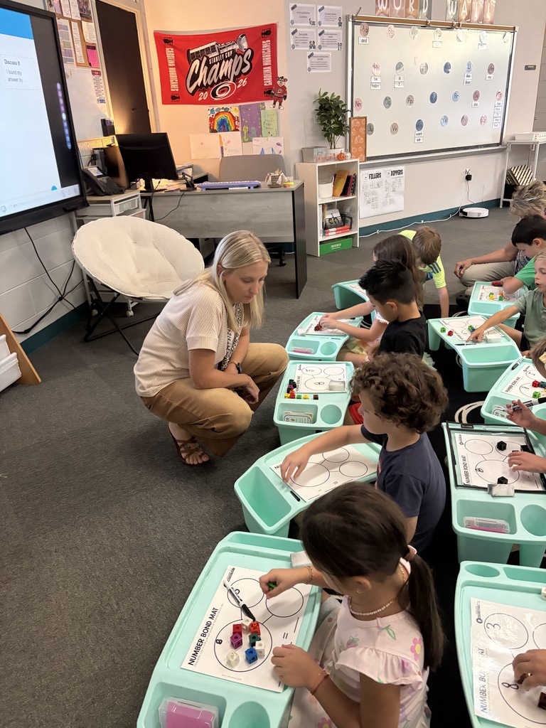 Classroom with a teacher and young students at desks, working on crafts or art projects.