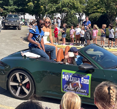 A green convertible with a sign reading "40 Khalil Ford" and people, including a man, sit in it.