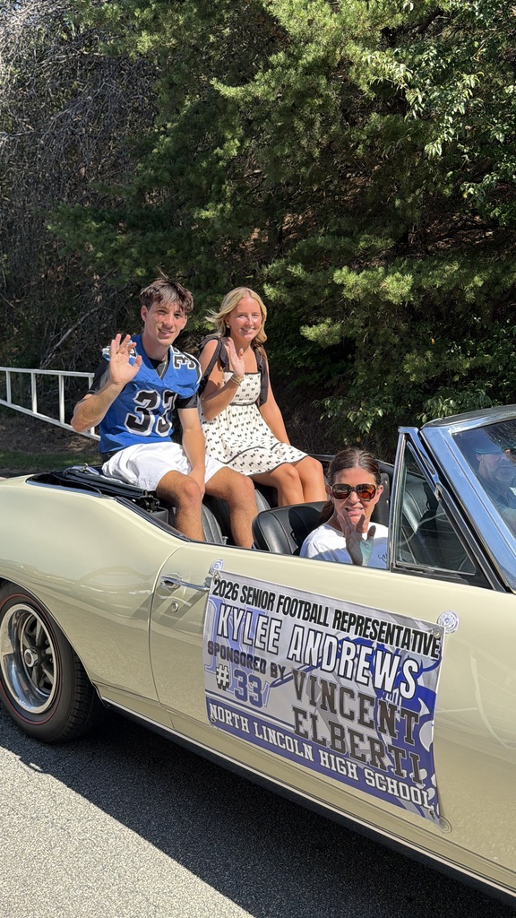 Three people in a convertible car. A man and a woman in the back. A woman in sunglasses in the front. Banner reads: Kylee Andrews, 2026 Senior Football Representative.