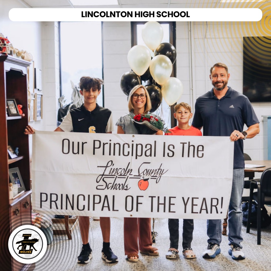 Four people hold a banner that reads, "Our Principal Is The Principal Of The Year!" with a bouquet of flowers in the middle.
