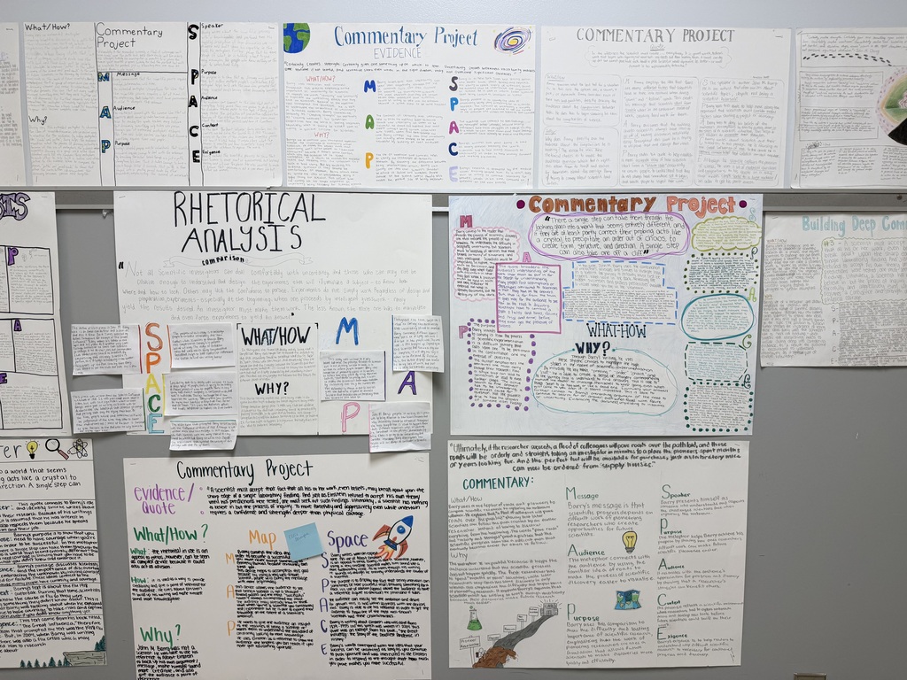 A bulletin board with multiple pieces of paper pinned to it, displaying text and diagrams.