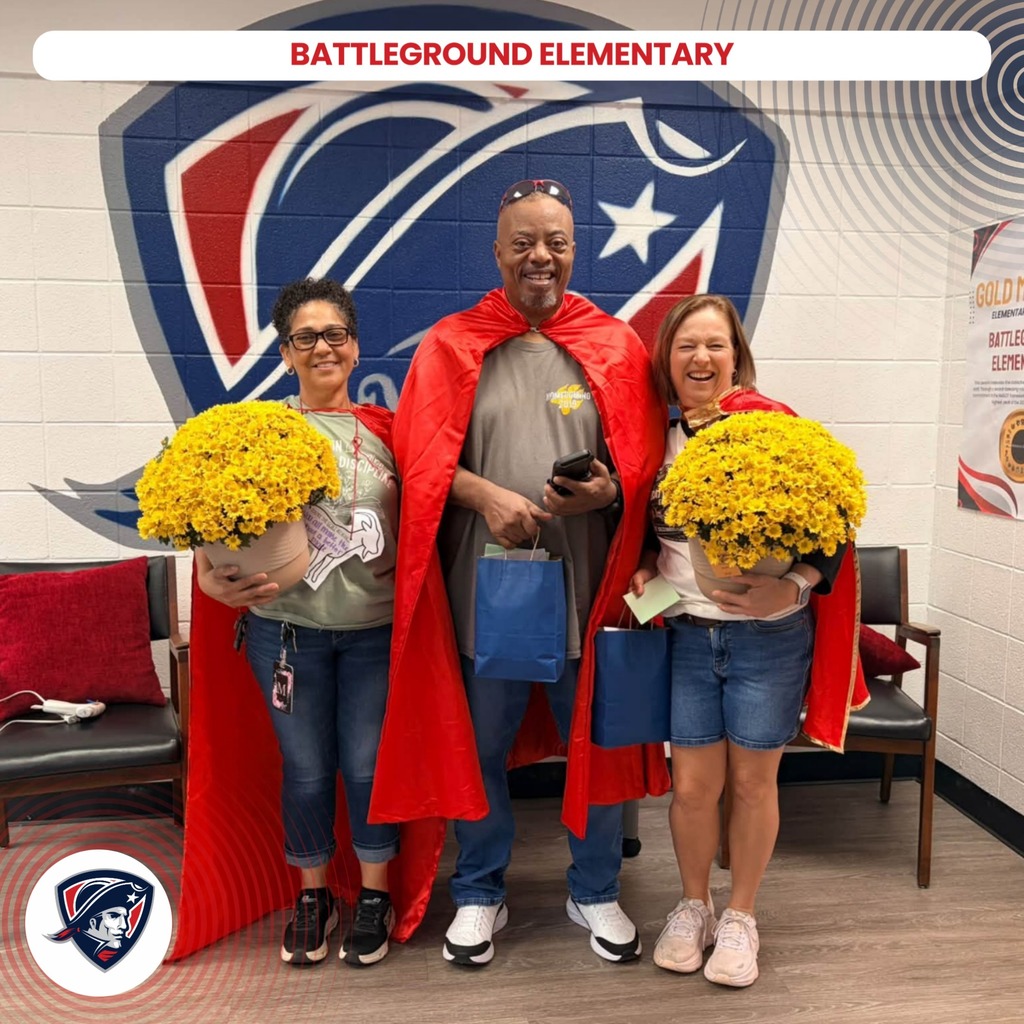 Three people stand in front of a wall with a red, white, and blue emblem. One holds yellow flowers, another has a red cape, and the third has a blue bag.