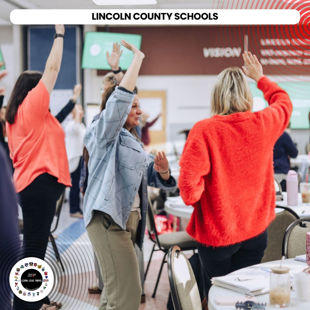 Several adults dance at a conference or workshop. One person wears an orange sweater. The background reads "Lincoln County Schools."