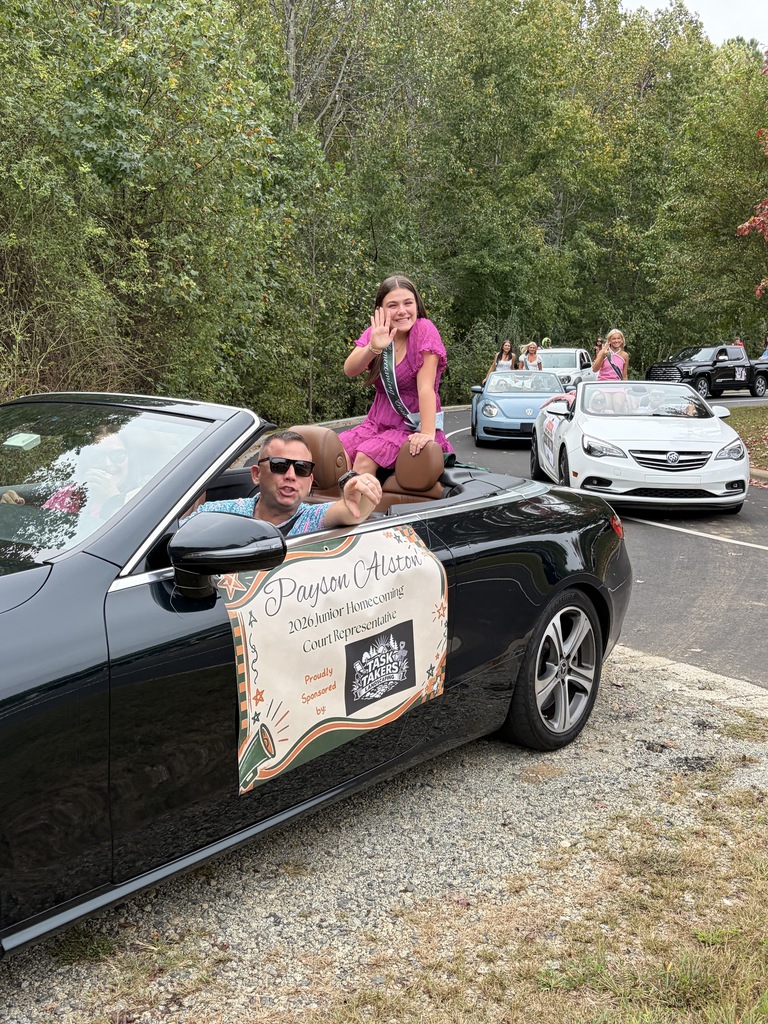 A black convertible car with a banner, with a man and a woman inside, on a road.