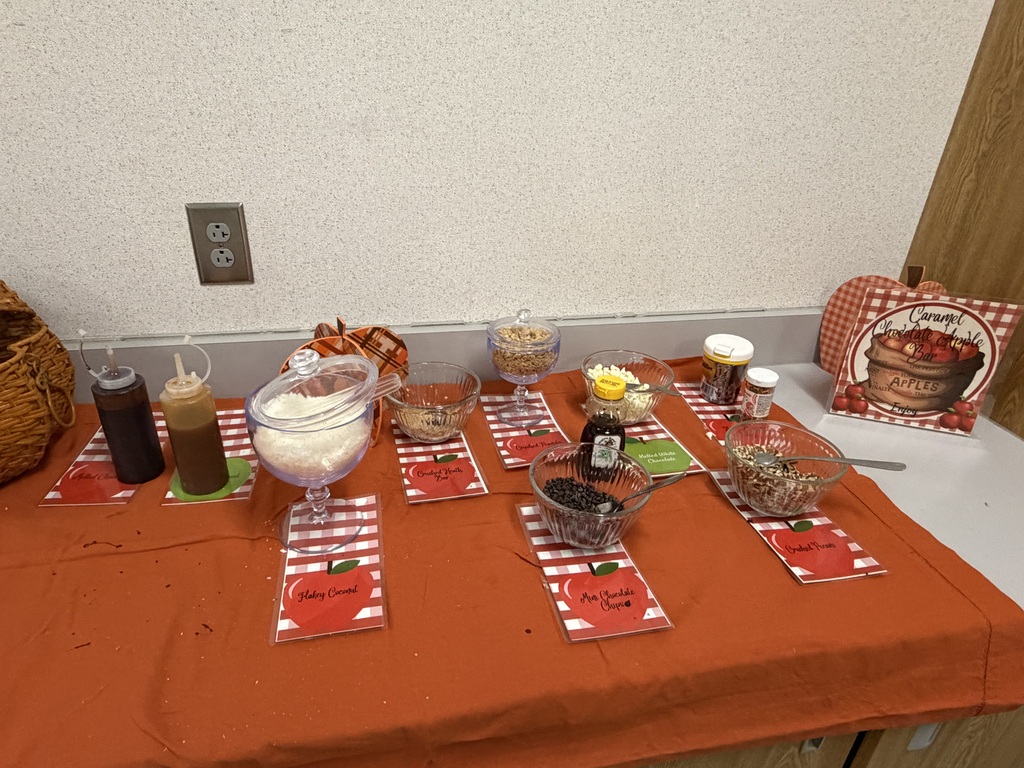 A table with an orange tablecloth displays a variety of food items, including sauces, dips, and bowls.