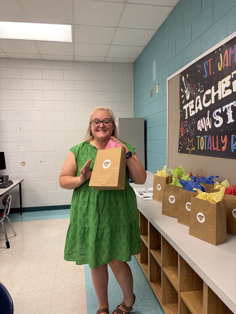 Person in green dress holding a bag stands next to shelves holding bags in a room.