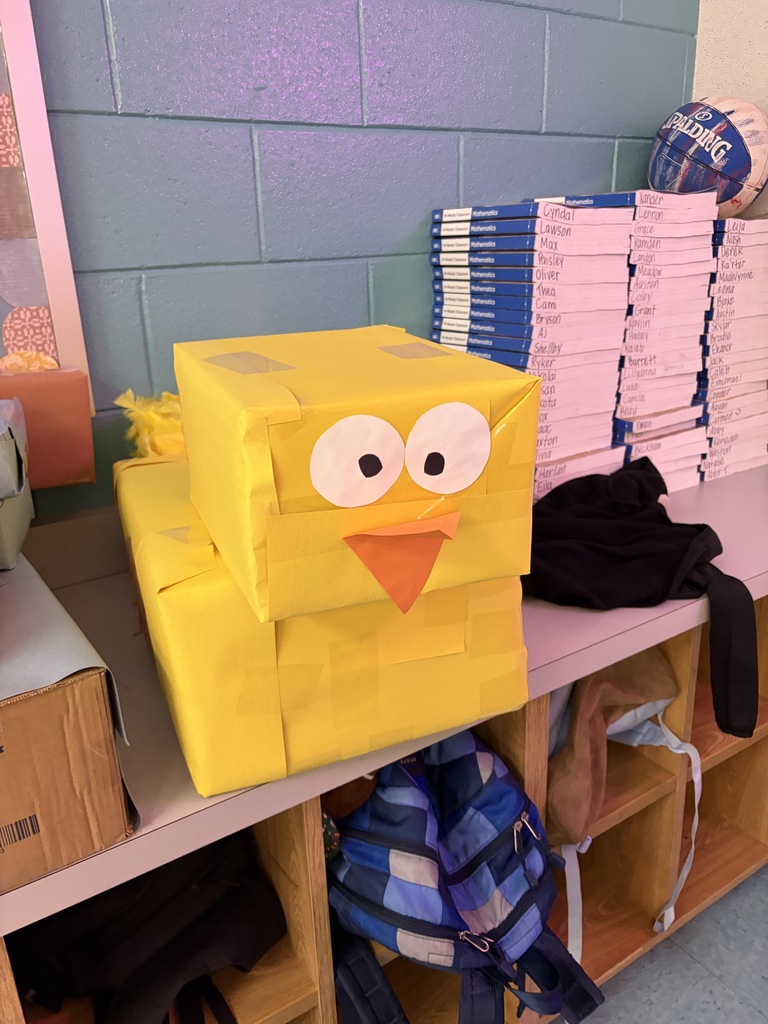 Bright yellow box with cartoon eyes and beak sits atop white shelves with bags, books, and boxes behind.