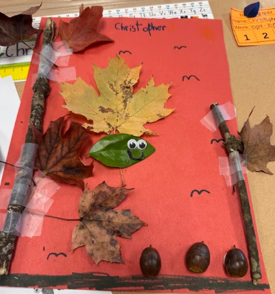 A red background displays leaves, twigs, and acorns. A leaf with eyes and a mouth is in the center.
