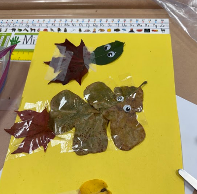 Art project of a turtle with leaf decorations on a yellow background. Behind is a ruler with alphabets.