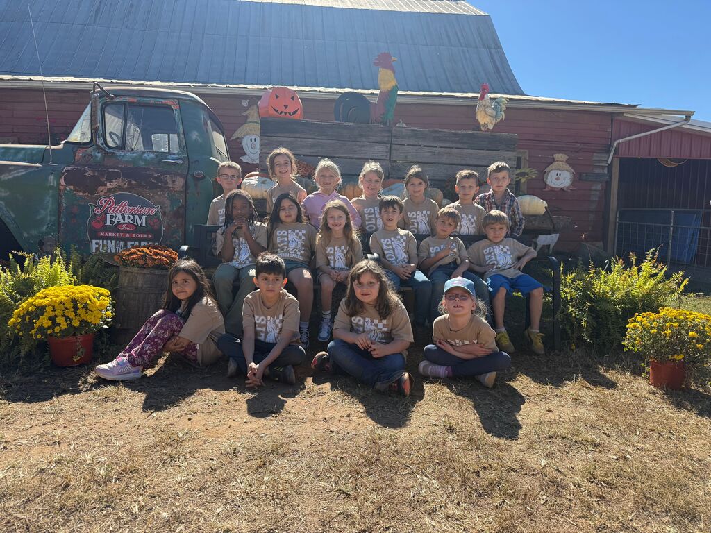 School group in matching shirts posing for a photo in front of a barn.