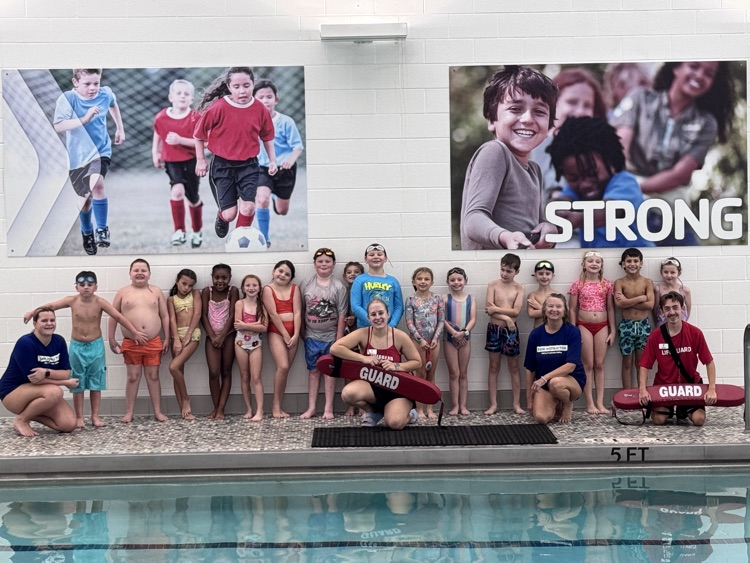 Group of children in swimwear by a pool, holding a lifeguard's equipment, with two posters behind them.