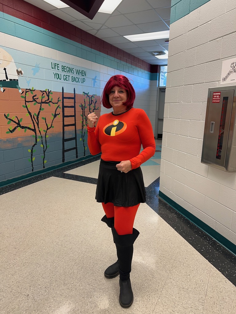 Person wearing a red costume with a black skirt and red boots posing in a hallway.