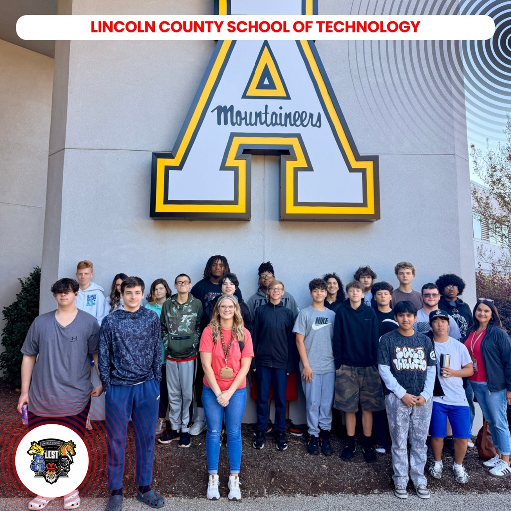 Students in front of a school building with a large letter A sign.