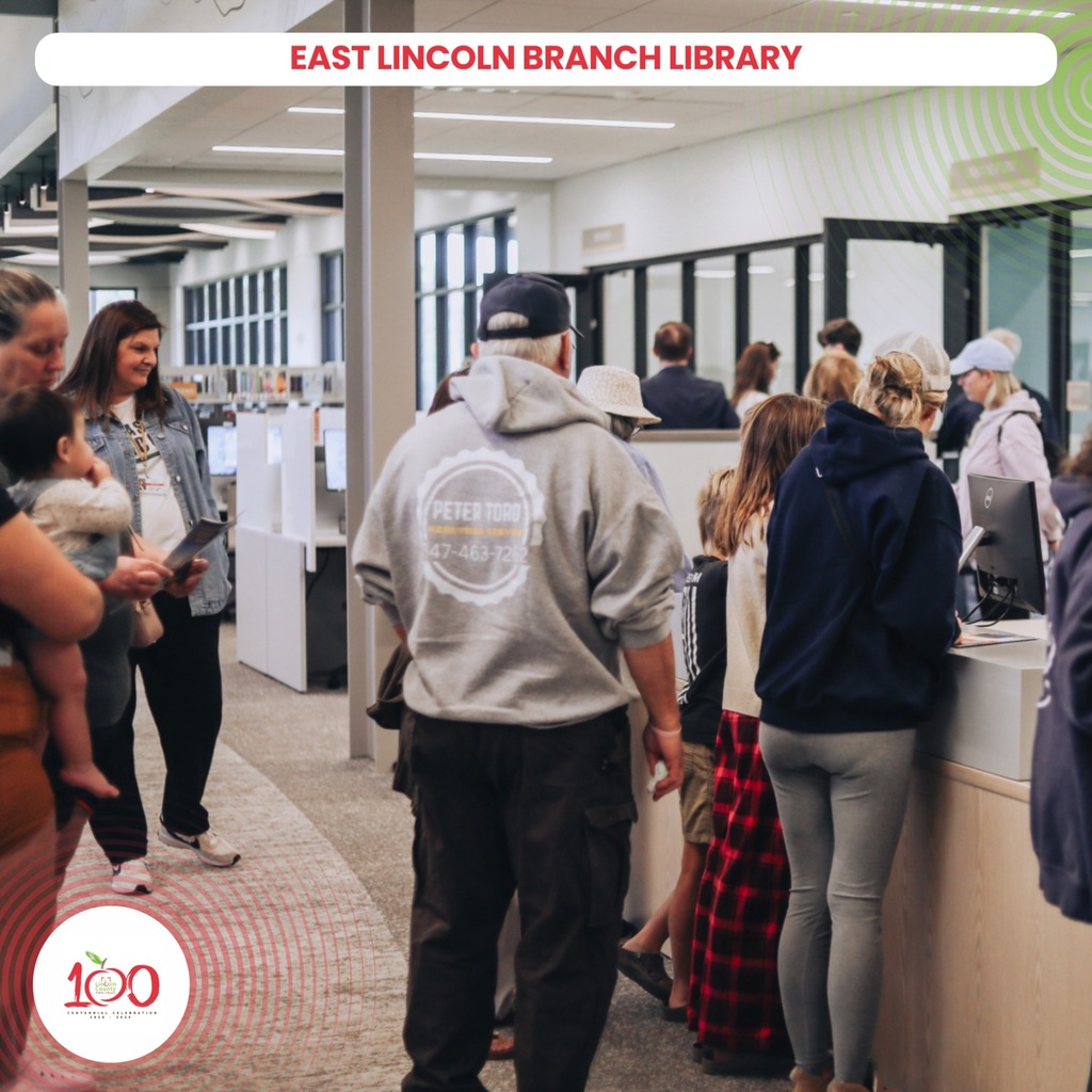 People in hoodies and sneakers standing in line at a counter in the East Lincoln Branch Library.