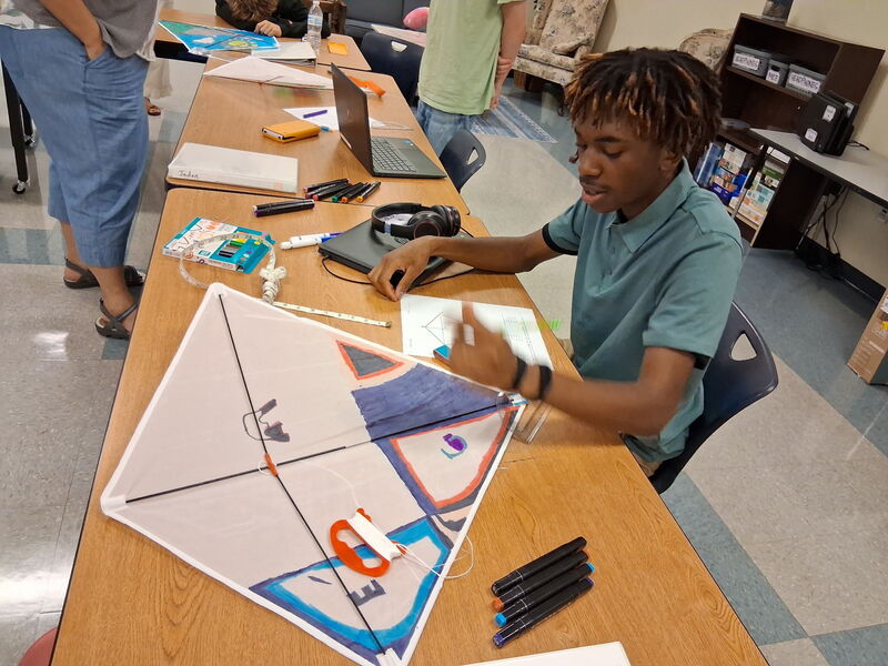 Student at a desk coloring a kite