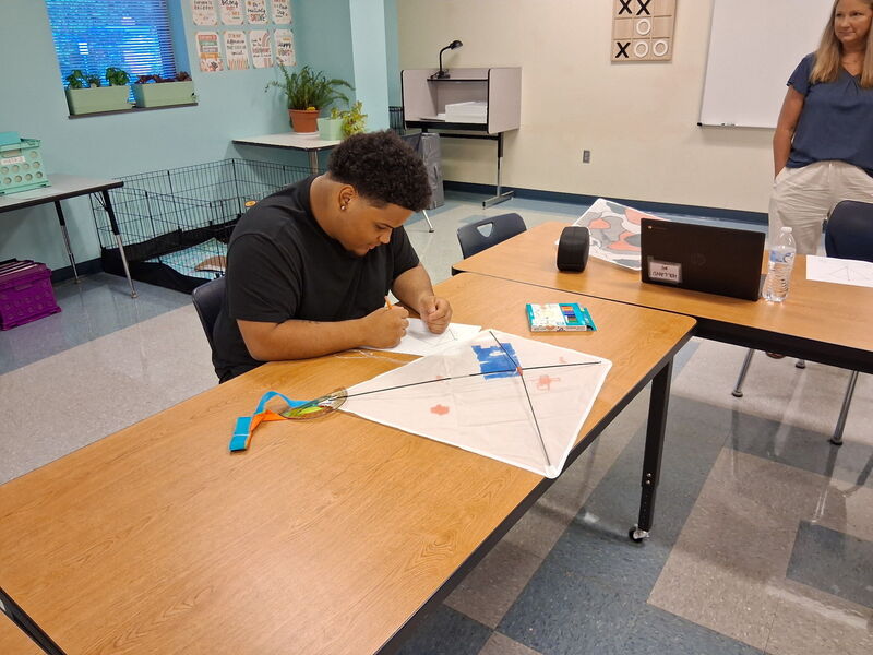 Student at a desk coloring a kite