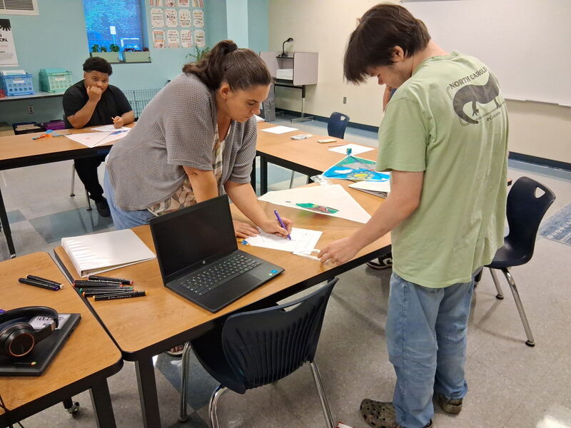 Teacher helps a students using a protractor at a table.
