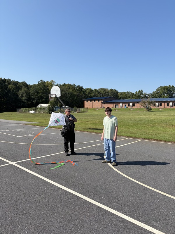 Student and police officer outside flying a kite.