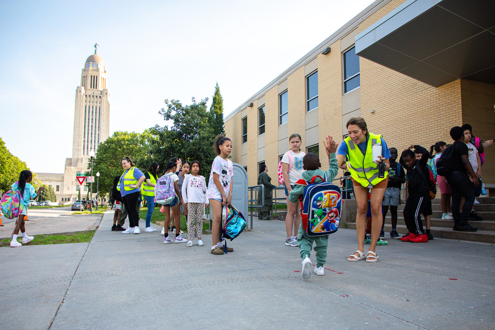 Staff members at McPhee Elementary welcome students with the Nebraska Capitol building in the background.