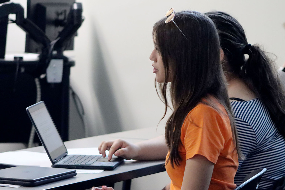 The Career Academy student Lauren asks a question to a witness during a mock trial. She served as the chief prosecutor. A fellow member of the prosecutorial team is taking notes on a laptop computer.