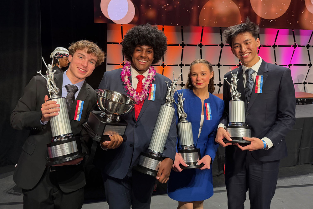 From left, East High School students Gavin Foust, Zach Johannes, Claire Rooney and Ethan Phan smile with their trophies at the National Speech and Debate Tournament in Richmond, Va. They are holding their trophies in front of a lights and a grid-style background.