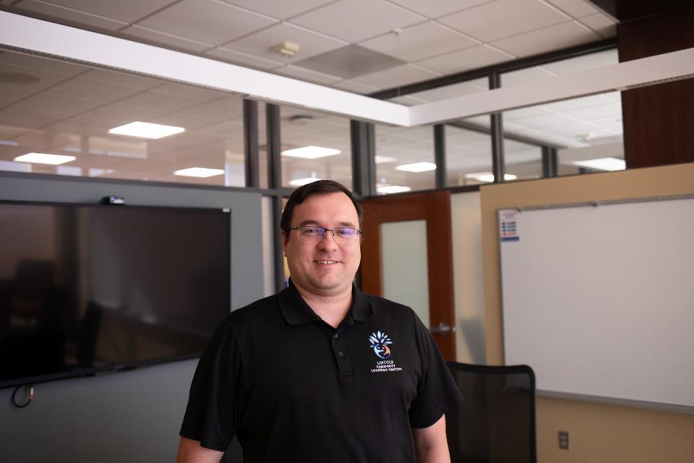 A man standing in a boardroom, wearing a black shirt.