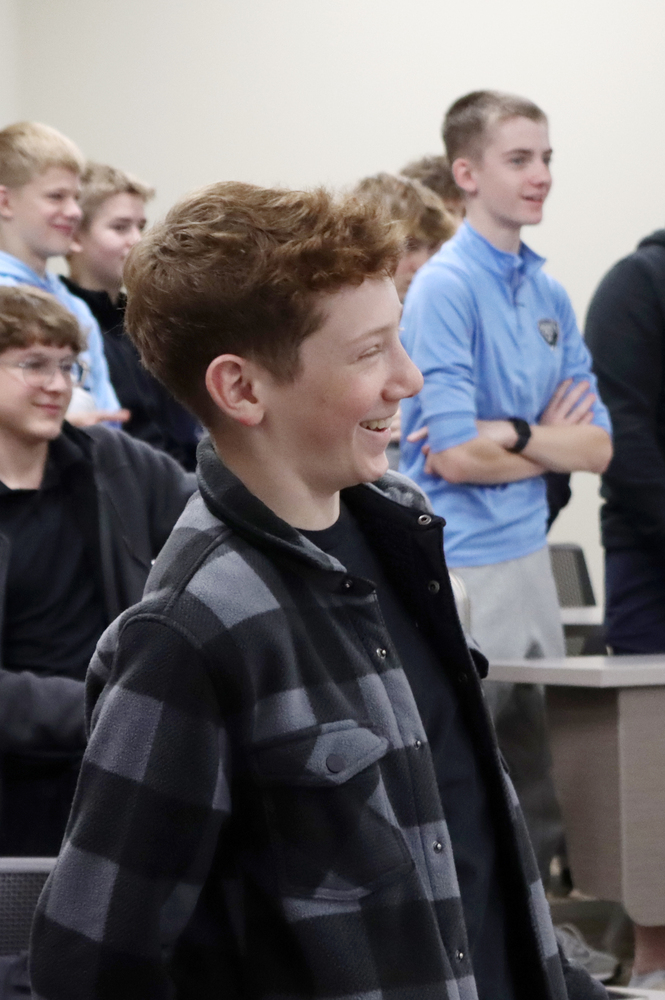 A Standing Bear student smiles during an activity in a classroom at the University of Nebraska-Lincoln. There are five students standing in the background.