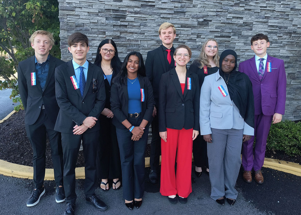 From left, Southwest High School students Mason Rathje, Hussein Keshk, Payton Wilkason, Mayuha Kadiri, Ezra Erickson, Claire Timperley, Addison Watchorn, Maarib Basi and Grant Johnson smile in a group photo. They are standing outside in front of mulched landscaping and a brick wall. They competed at the National Speech and Debate Tournament.