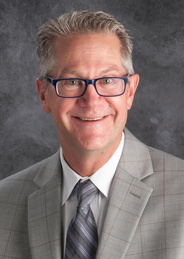 Headshot of LPS Superintendent John Skretta in a grey suit.