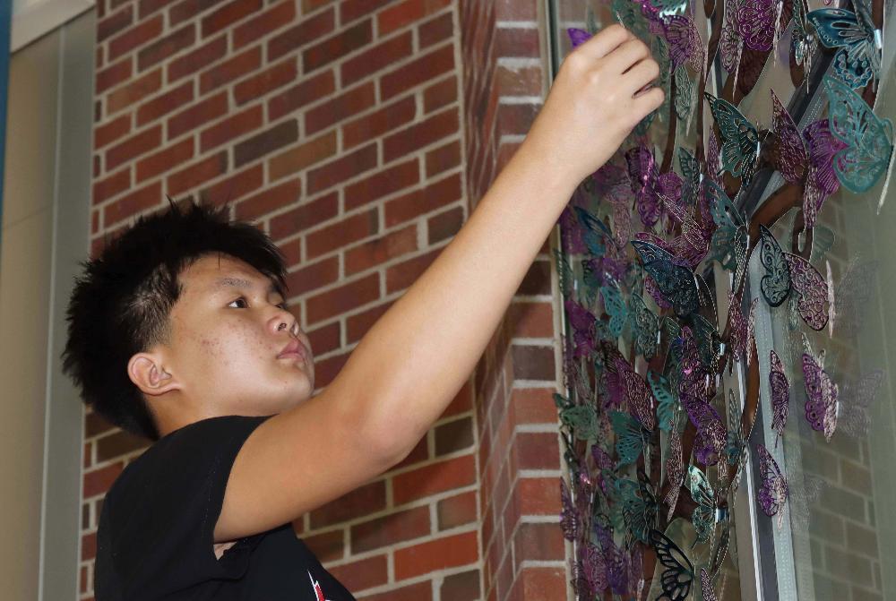 Park Middle School student Tha places a plastic butterfly on a cafeteria window to raise awareness about mental health as part of the Hope Squad activity.