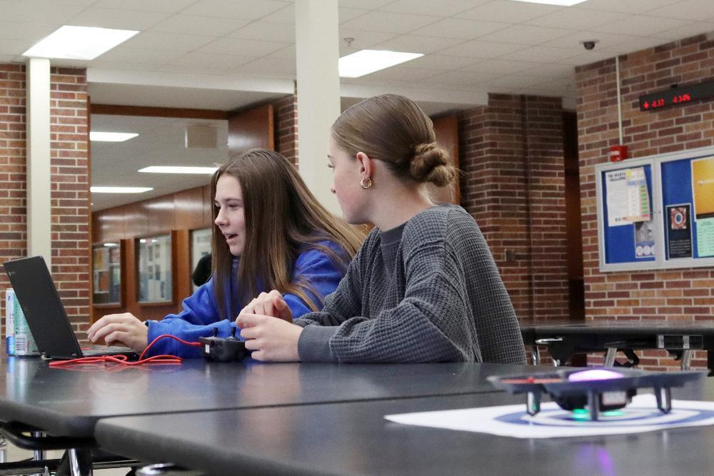 Two East High School students smile as they prepare to launch their drone in a Computer Science Foundations class.