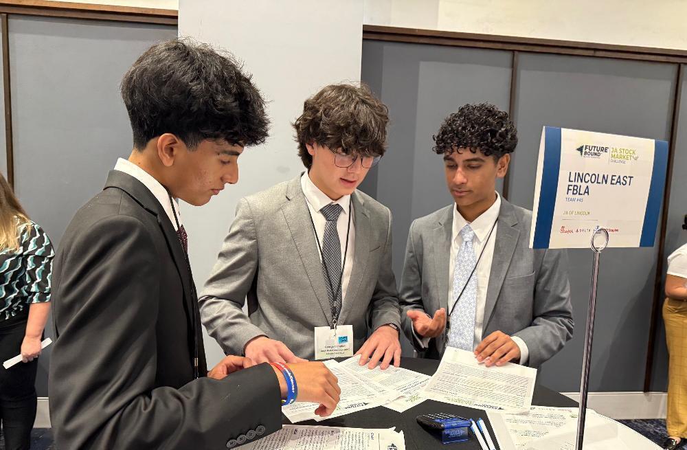 From left, East High School students Ronav, George and Anish look over pieces of paper that detail their investment plans for the Junior Achievement Stock Market Challenge. They finished eighth out of 45 teams at the national contest in Atlanta.