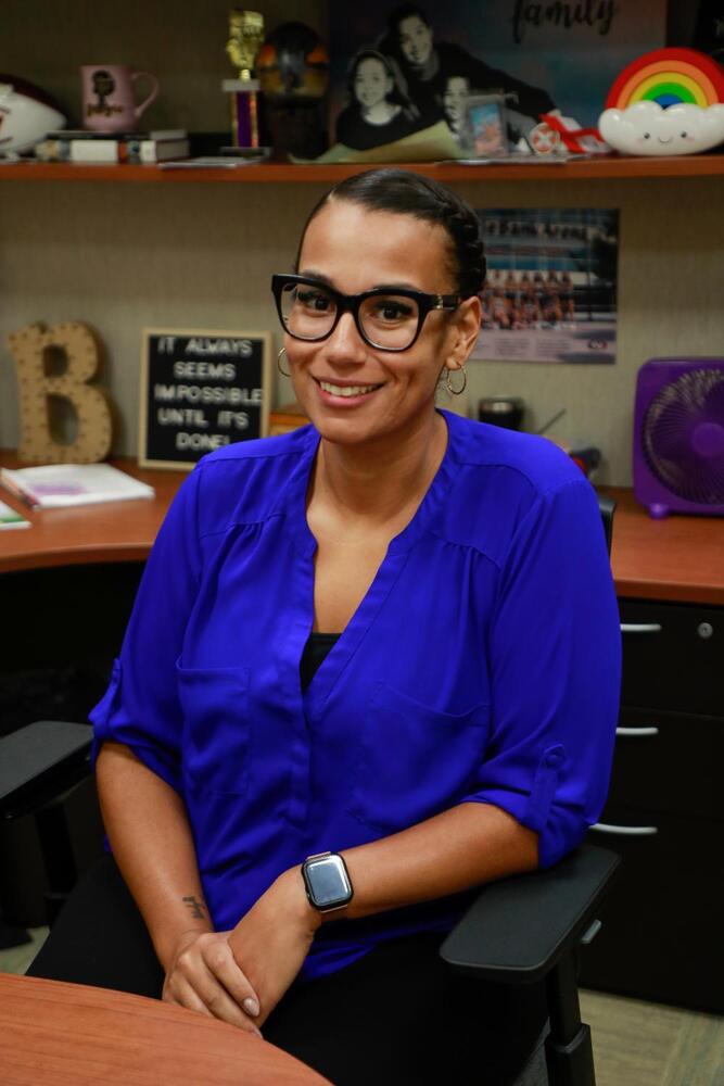 A woman sitting at a desk wearing a blue shirt.